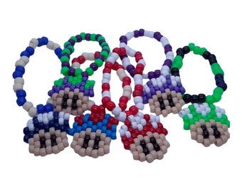 May include: A set of six colorful beaded bracelets with mushroom-shaped charms. The bracelets are made with white, red, blue, green, and purple beads. The charms are made with white, red, blue, green, and purple beads.