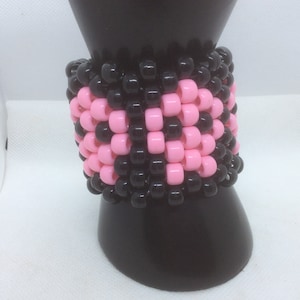 Op de afbeelding: Een armband van zwarte en roze kralen met een geometrisch patroon.