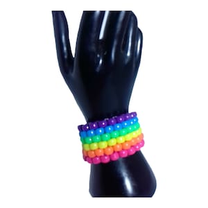 May include: A rainbow-colored beaded bracelet with multiple rows of colorful beads. The bracelet is made of small, round beads in shades of purple, blue, green, yellow, orange, and pink.