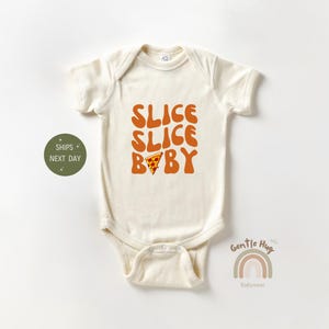 May include: Cream-colored baby bodysuit with the text "SLICE SLICE BABY" in orange, along with a pizza slice graphic. The short-sleeved onesie is designed for infants and toddlers.