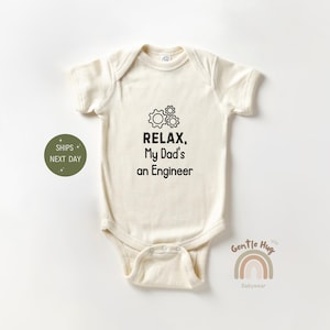 May include: A cream-colored baby onesie with short sleeves and a black graphic that says "Relax, My Dad's an Engineer" with a drawing of three gears.