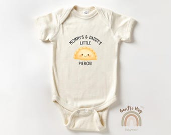 Może przedstawiać: Kremowe body niemowlęce z krótkim rękawem. Z przodu napis "Mommy's & Daddy's Little Pierogi" nad uśmiechniętą ilustracją pieroga. Na dole tęcza i napisy "Gentle Hug Babywear".