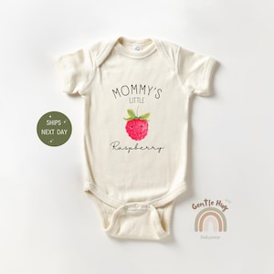 May include: Cream-colored baby onesie with the text "Mommy's Little Raspberry" and a watercolor illustration of a raspberry. The onesie has short sleeves and a snap closure. The design includes a cute raspberry graphic.