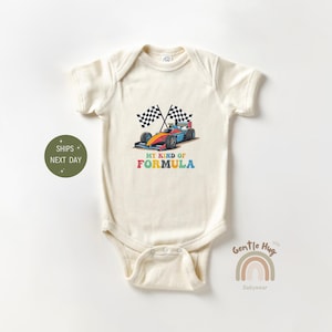 May include: A cream-colored baby onesie with a colorful graphic of a race car and checkered flags. The text "My Kind of Formula" is printed in rainbow colors below the car.