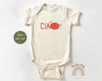 May include: Cream-colored baby onesie with short sleeves. The onesie features the word "CIAO" in red letters above a smiling tomato illustration. The onesie is made of soft material and is designed for comfort.