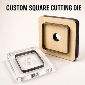 Può includere: Una fustella quadrata personalizzata con base in legno chiaro, lama quadrata in metallo scuro e foro centrale, abbinata a un blocco quadrato in acrilico trasparente con un contorno quadrato in metallo scuro e un piccolo anello centrale.