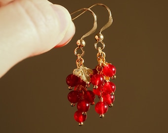 Pendientes artesanales de grosella roja, chapados en oro, con forma de racimo de bayas.