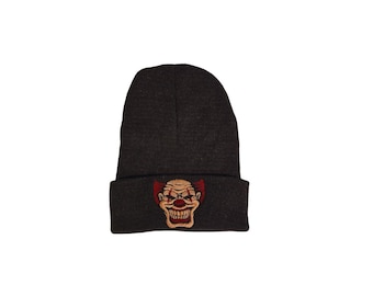 May include: A black beanie with a red and white clown face embroidered on the front.