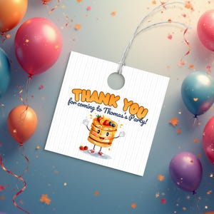Puede incluir: Una etiqueta de regalo blanca con el texto "THANK YOU for coming to Thomas's Party!" y una ilustración de dibujos animados de panqueques. La etiqueta está rodeada de globos y confeti de colores, creando un ambiente festivo.