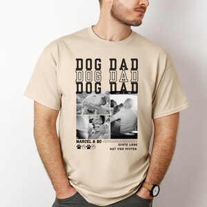 May include: Beige t-shirt with the words "DOG DAD" in a stacked design. Below are four black and white photos of dogs and people. The text "MARCEL & BO" and "ECHTE LIEBE HAT VIER PFOTEN" are also printed on the shirt.