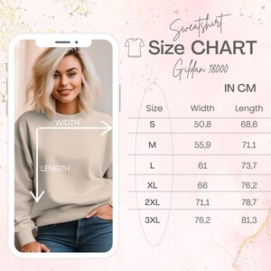 May include: A beige sweatshirt with a size chart in centimeters. The chart shows width and length measurements for sizes S to 3XL. The text on the chart reads "Sweatshirt Size CHART Gildan 18000 IN CM".