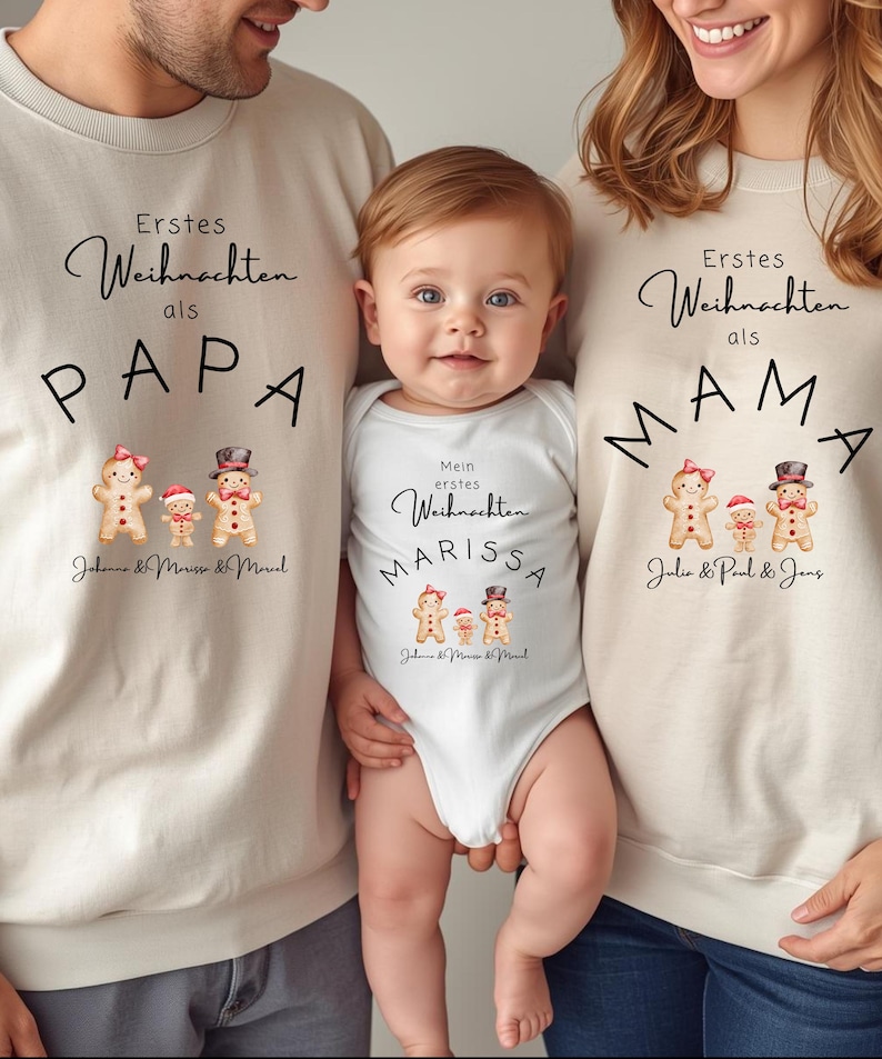 May include: A family wearing matching beige sweatshirts and a white onesie. The sweatshirts say "Erstes Weihnachten als PAPA" and "Erstes Weihnachten als MAMA" with gingerbread family graphics. The onesie says "Mein erstes Weihnachten MARISSA".