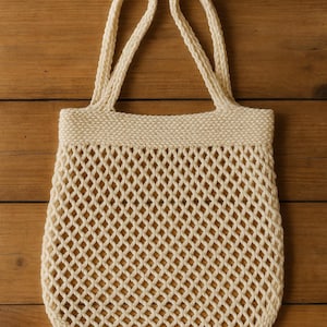 May include: Cream-coloured knitted tote bag with a diamond-patterned net design. The bag has two sturdy handles and a wide, reinforced top. The bag is made of a thick, textured yarn, and is suitable for carrying groceries or other items.