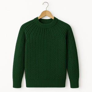 Puede incluir: Un suéter verde oscuro con cuello redondo y mangas largas. El suéter está hecho de una tela de punto texturizada con un diseño acanalado. Cuelga de una percha de madera.