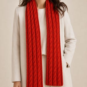 May include: A vibrant red scarf featuring a prominent vertical cable knit pattern. The scarf is long and rectangular, displaying a thick, textured weave with repeating twisted rope-like columns that run the entire length of the accessory.