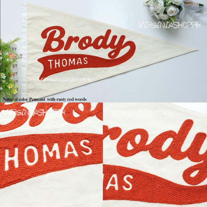May include: A triangular off-white felt pennant featuring the name Brody in large, textured, rusty red script lettering. Below the name, the word THOMAS is displayed in white capital letters on a rusty red, banner-shaped background.