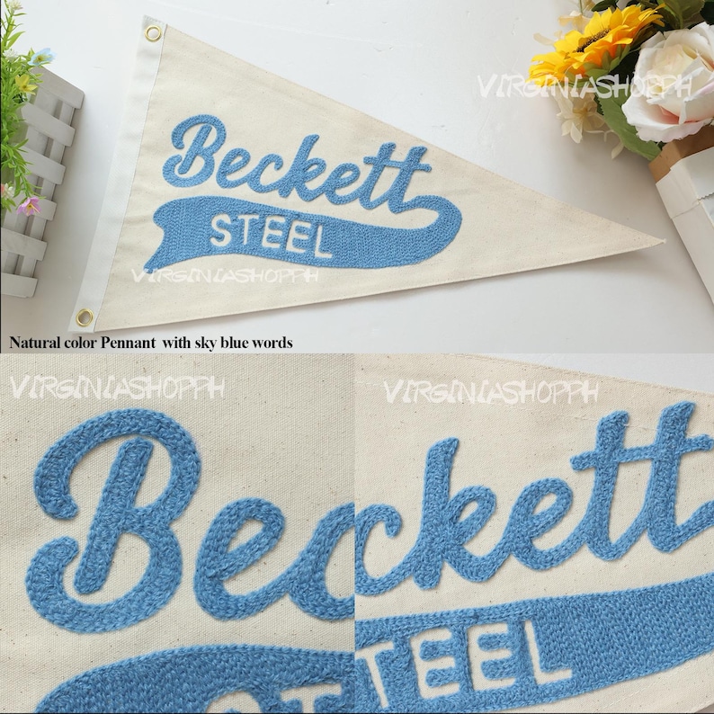 May include: A triangular off-white canvas pennant featuring the embroidered text Beckett STEEL in sky blue. The pennant includes two metal grommets along the left vertical edge for hanging. The design is shown in full and in close-up detail.