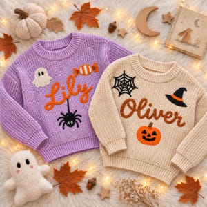 May include: Two long-sleeve knit sweaters, one light purple and one beige, featuring embroidered Halloween motifs. The purple sweater displays the name Lily, a ghost, a spider, and a candy. The beige sweater displays the name Oliver, a spiderweb, a pumpkin, and a witch hat.