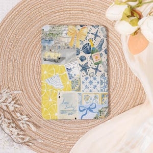 May include: A rectangular decorative item with a collage of images, including a yellow car, lemons, seashells, and a champagne bottle. The text "how lucky are we" is visible. The color scheme includes yellow, blue, and white.
