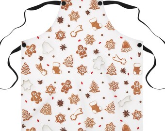May include: White apron with a Christmas gingerbread cookie pattern. The apron has adjustable straps and a pocket.