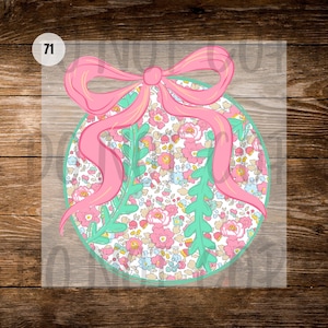May include: A round floral design with a pink bow and green accents. The design features a light blue outline and a floral pattern with pink, blue, and yellow flowers. The number "71" is in the upper left corner.
