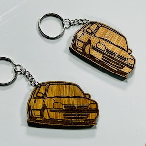 Peut inclure: Deux porte-clés en bois avec un motif de voiture. Les porte-clés sont en bois brun clair et présentent un motif de voiture découpé au laser. Chaque porte-clés est doté d'un anneau et d'une chaîne de couleur argentée.