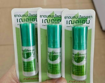 Puede incluir: Tres inhaladores de aromaterapia cilíndricos verdes y blancos en blíster. El embalaje presenta texto en idioma extranjero y un gráfico de hoja verde. Los inhaladores se sostienen en una mano.