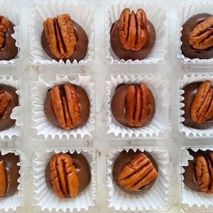 Puede incluir: Una taza de cerámica blanca con un asa negra y el texto "But First, Coffee" en negro y negrita. La taza está sobre una superficie de madera. La taza está vacía.