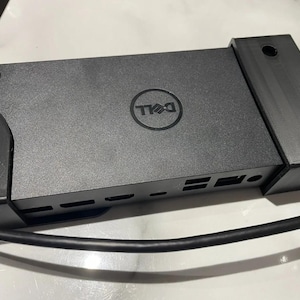 May include: A black Dell computer with a stand and multiple ports on the side. The computer is connected to a black cable.