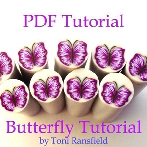 Könnte beinhalten: PDF-Tutorial zum Herstellen von Polymer Clay-Schmetterlingsstäben. Das Bild zeigt acht fertige Stäbe mit lila und weißen Schmetterlingen auf weißem Hintergrund. Der Text "Butterfly Tutorial by Toni Ransfield" befindet sich am unteren Rand des Bildes.