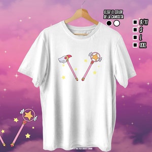 May include: White t-shirt with a pink and yellow cartoon image of two wands with stars on top. The text "Elige el color de la camiseta" is in the top right corner of the image.