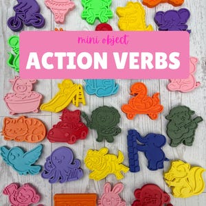 May include: A collection of colorful plastic mini objects featuring various animals and shapes, including a bear on a bike, a frog on a swing, and a snake on a skateboard. A pink rectangular overlay displays the text mini object ACTION VERBS.