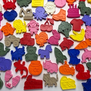 May include: A collection of colorful, die-cut shapes in various designs, including animals, food items, and objects. The shapes are in a variety of colors, such as red, blue, green, and yellow. The collection includes a giraffe, a pear, and a train.