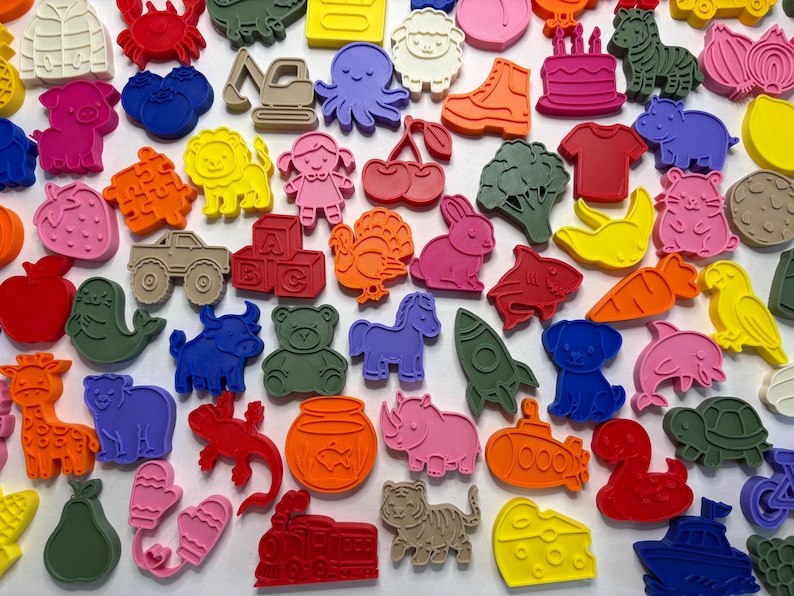May include: A collection of colorful plastic cookie cutters in various shapes including animals, vehicles, food items, and letters. The assortment features vibrant shades of red, blue, yellow, green, pink, orange, and tan, arranged in a dense pattern.