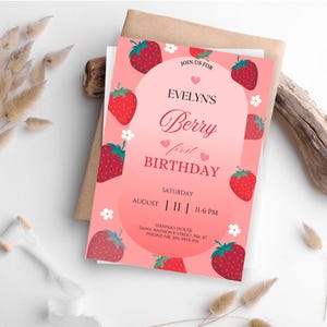 May include: Pink birthday invitation with a strawberry theme. The invitation says "Join us for Evelyn's Berry First Birthday" and includes the date and time of the party.