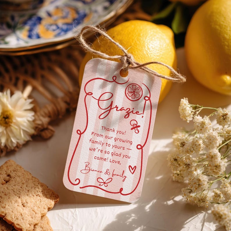 Puede incluir: Una etiqueta de regalo a rayas rosas y blancas con la palabra "Grazie!" en escritura roja. La etiqueta est&aacute; atada con hilo a un lim&oacute;n amarillo. La etiqueta tambi&eacute;n dice "Thank you!" y "Love, Bianca & family."