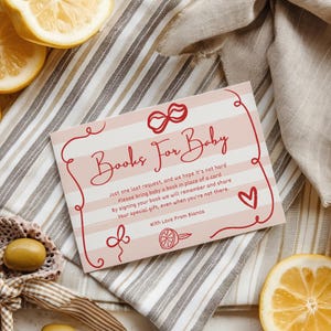 Puede incluir: Tarjeta de invitaci&oacute;n a un baby shower con el texto "Books For Baby" en una fuente decorativa. La tarjeta tiene un fondo a rayas rosas y blancas con elementos decorativos rojos y un coraz&oacute;n. Limones y aceitunas en el fondo.