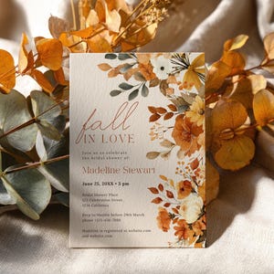 Könnte beinhalten: Eine Brautparty-Einladung mit den Worten "fall in love" in eleganter Schrift. Die Einladung zeigt Aquarell-Blumenarrangements in Orange-, Gelb- und Weißtönen. Die Details umfassen den Namen der Braut, Datum, Uhrzeit und Ort.