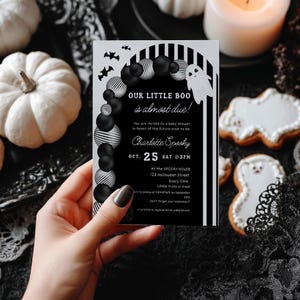 May include: A Halloween-themed baby shower invitation with the text "OUR LITTLE BOO is almost due!" in black and white. The invitation features a ghost illustration, balloons, and bats. The date is October 25th.