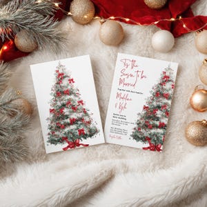 May include: Two white Christmas wedding invitations with a watercolor Christmas tree design. The tree is decorated with red bows. The text on the invitation reads "Tis the Season to be Married" and includes the names Madeline & Kyle.