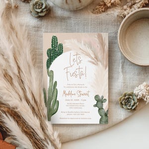 May include: A beige invitation card with the words "Let's Fiesta!" and details for a bridal brunch. The design features watercolor cacti and pampas grass. The card is on a neutral linen surface.