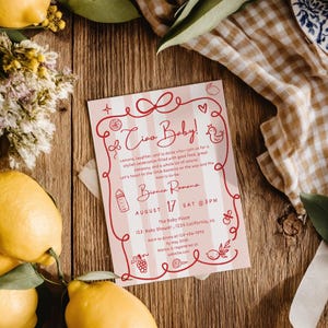Puede incluir: Una invitaci&oacute;n a un baby shower con un dise&ntilde;o de rayas rosas y blancas, con el texto "Ciao Baby!" y los detalles del evento. La invitaci&oacute;n est&aacute; decorada con ilustraciones de limones y otros elementos, sobre una superficie de madera.