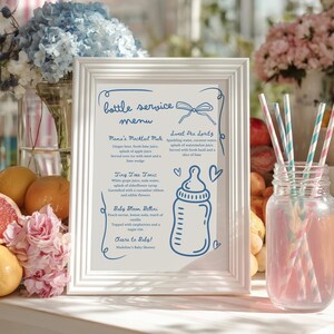 May include: A white framed menu for a baby shower, featuring a blue illustration of a baby bottle and drink recipes. The menu includes drinks like Mama's Mocktail Mule and Sweet Pea Spritz. Pink and blue striped straws are in a glass jar.