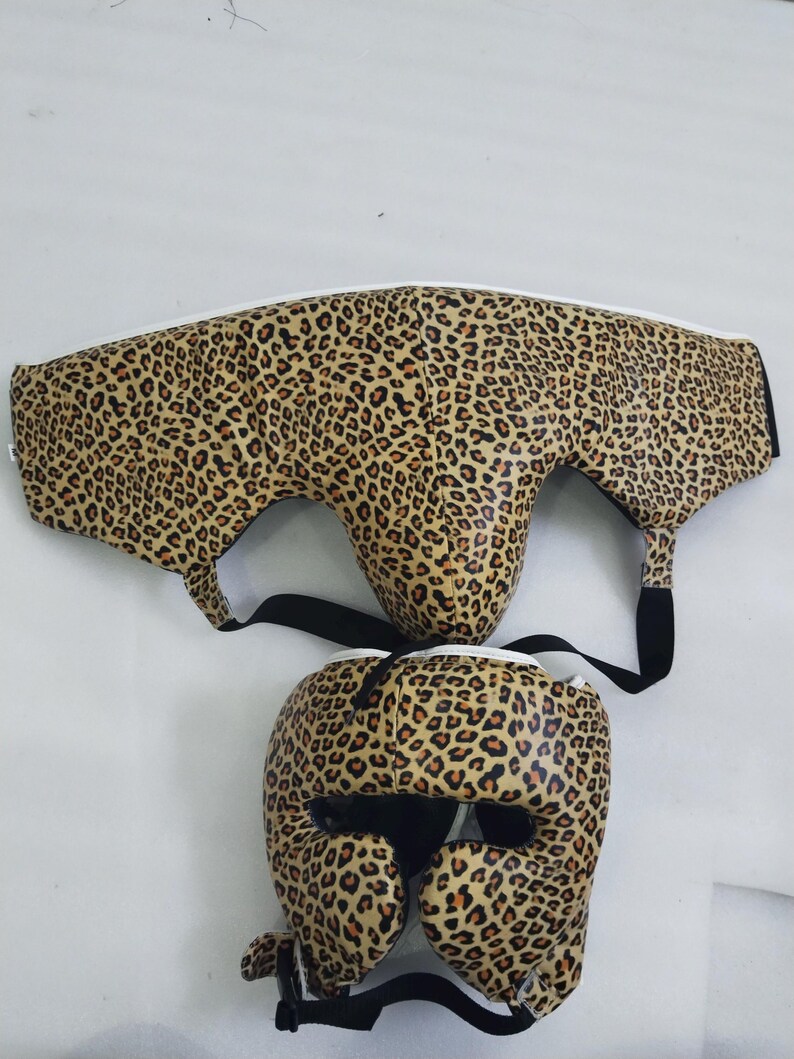 Puede incluir: Juego de protecci&oacute;n de boxeo de dos piezas. El equipo de protecci&oacute;n presenta un estampado de leopardo marr&oacute;n con detalles y correas negras. El casco tiene aberturas para los ojos, la nariz y las orejas.