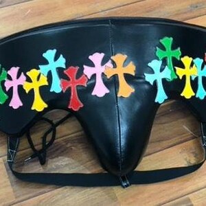 May include: Black leather protective cup with colorful cross appliques. The crosses are in various colors, including green, pink, yellow, red, and blue. The cup has a black strap and a drawstring.