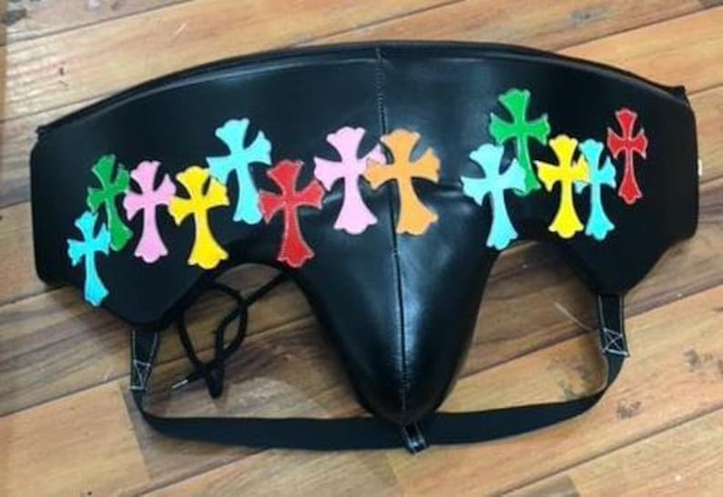 May include: Black leather protective cup with colorful cross appliques. The crosses are in various colors, including green, pink, yellow, red, and blue. The cup has a black strap and a drawstring.
