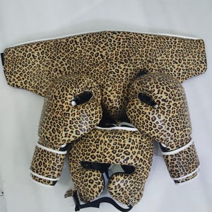 Puede incluir: Un conjunto de boxeo con estampado de leopardo. El conjunto incluye un protector de cabeza, un protector de pecho y guantes de boxeo. Los guantes y el casco tienen acolchado interior negro y ribete blanco.