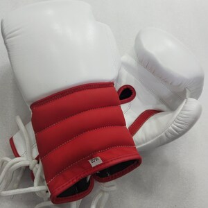 Pu&ograve; includere: Paio di guantoni da boxe bianchi e rossi. I guantoni hanno una parte superiore imbottita bianca e una zona del polso imbottita rossa. I guantoni sono allacciati con lacci bianchi. L'etichetta sulla zona del polso recita "16-OZ".