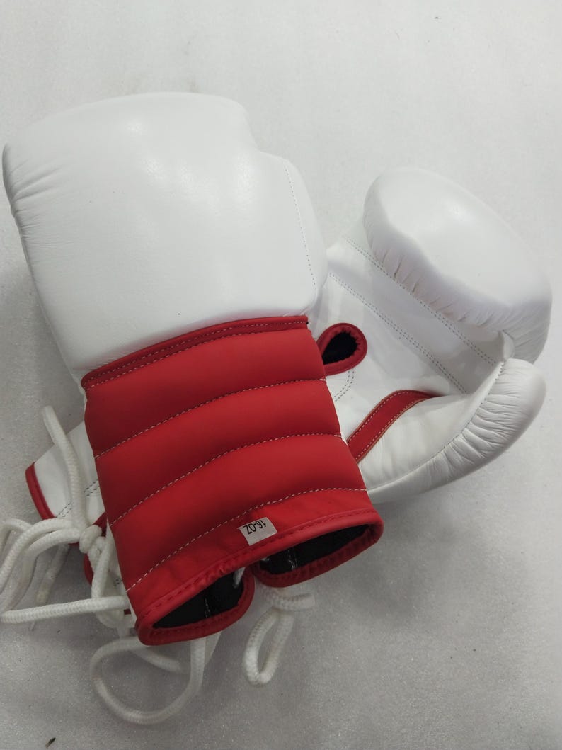 Pu&ograve; includere: Paio di guantoni da boxe bianchi e rossi. I guantoni hanno una parte superiore imbottita bianca e una zona del polso imbottita rossa. I guantoni sono allacciati con lacci bianchi. L'etichetta sulla zona del polso recita "16-OZ".
