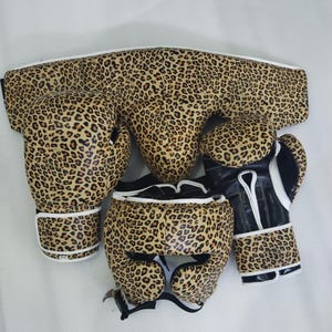 Puede incluir: Un conjunto de boxeo con estampado de leopardo. El conjunto incluye guantes de boxeo, un protector de cabeza y un protector de ingle. Los guantes tienen detalles en blanco y negro. El conjunto est&aacute; dise&ntilde;ado para la protecci&oacute;n durante el entrenamiento y los combates de boxeo.